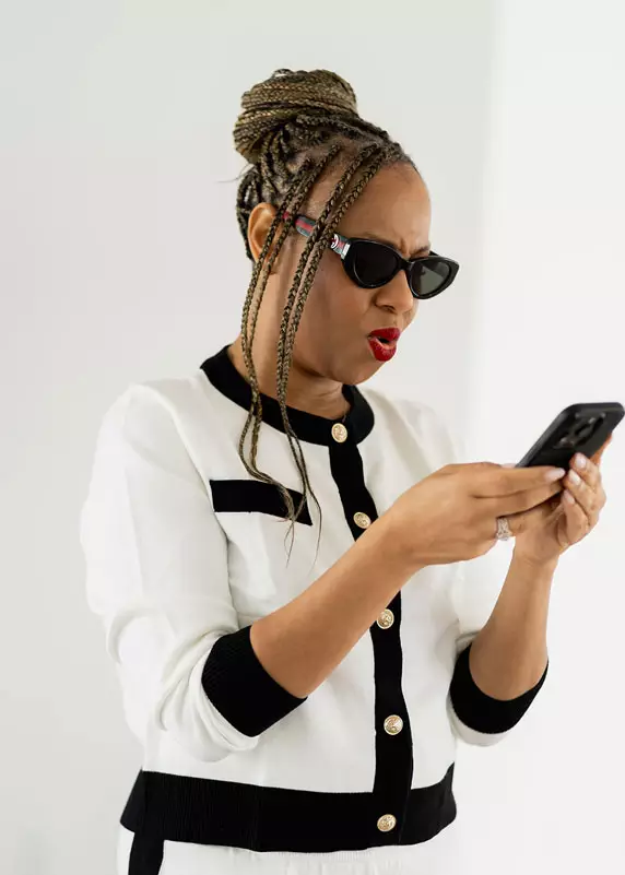 Freda Richards wearing sunglasses and holding a phone with a playful expression.