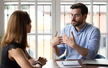 An auditor talks with a colleague in an office setting