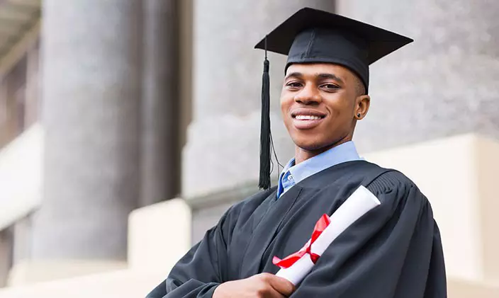 African American college graduate smiling and holding diploma for his B A degree