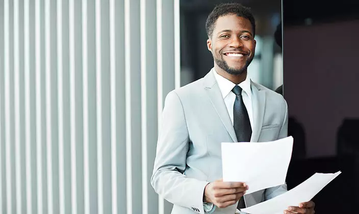 Male business analyst smiling with paperwork