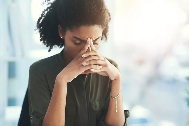 An anxious employee sits with her head in her hands.