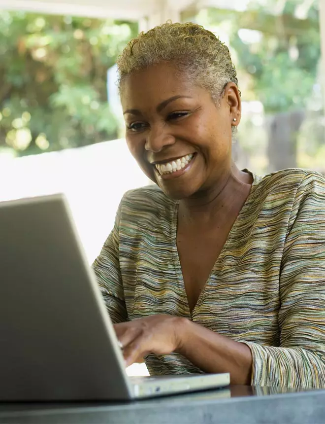 Student smiles as she attends class online from her laptop