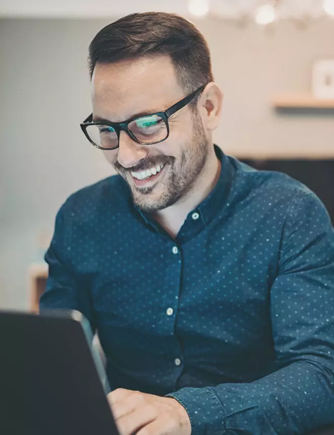 Business professional smiles as he attends class on his laptop at lunch