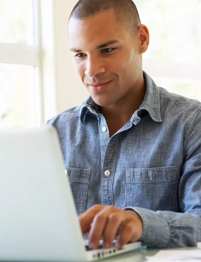 Student smiles as he reads a reply from his teacher on his laptop