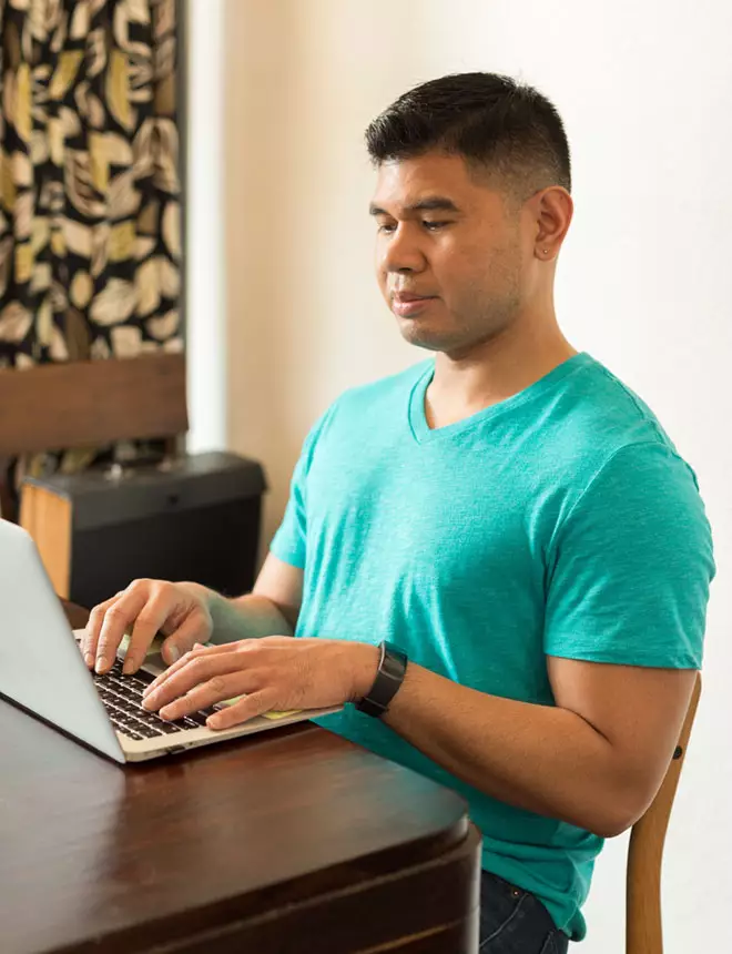 Student in his employer's breakroom reviews his school work on his laptop