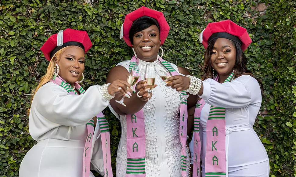 The three friends wear their doctoral berets while toasting their graduation