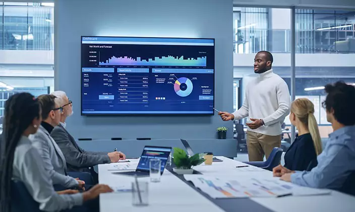 Man presents on a flat screen television to colleagues in a high-tech boardroom