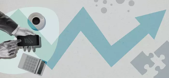 A business man's hands looking at a phone next to a calculator to signify business management consultant