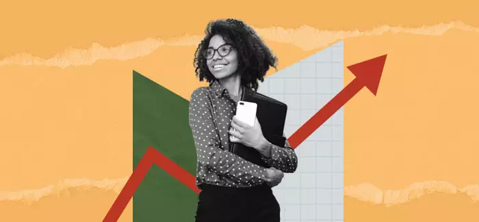 Woman holding a notebook and mobile phone standing in front of a graph with a red arrow pointing upward to signify what you can do with a business degree