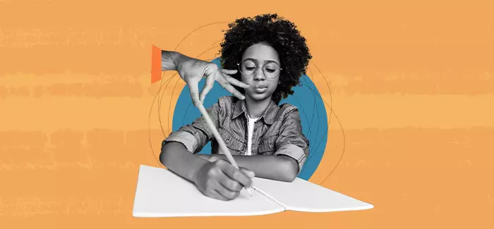 A teacher's hand reaching out to touch a student's pencil while they write to signify curriculum and instruction