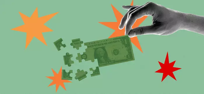 A hand holding a dollar bill by one corner while it breaks up into pieces shapes like puzzle pieces to represent capital allocation