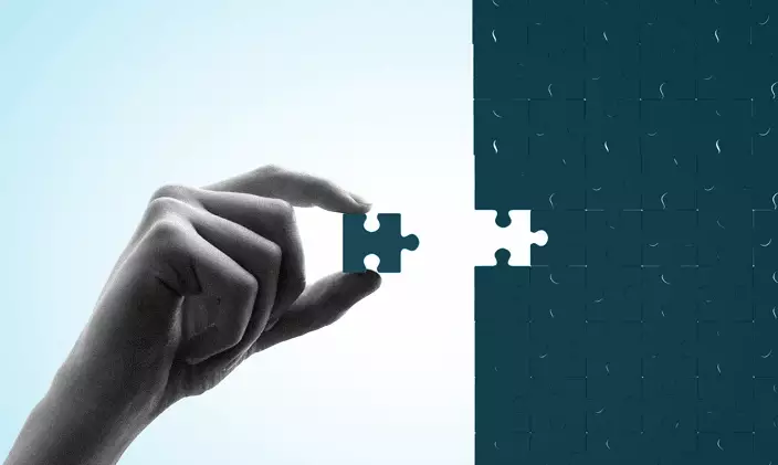 A hand placing a puzzle piece into a missing slot of a larger puzzle to signify finishing a unique value proposition