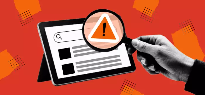 Hand with magnifying glass looking at a screen with a warning sign to signify red teaming