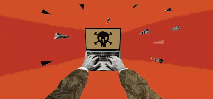 A man's hands on an open laptop with a skull and crossbones on the screen warning about malware types.