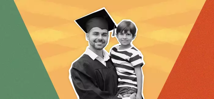 A single parent in graduation garb holding their child for a photo