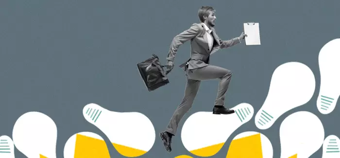 A male business intelligence analyst with a briefcase and clipboard running uphill on a staircase made of lightbulbs