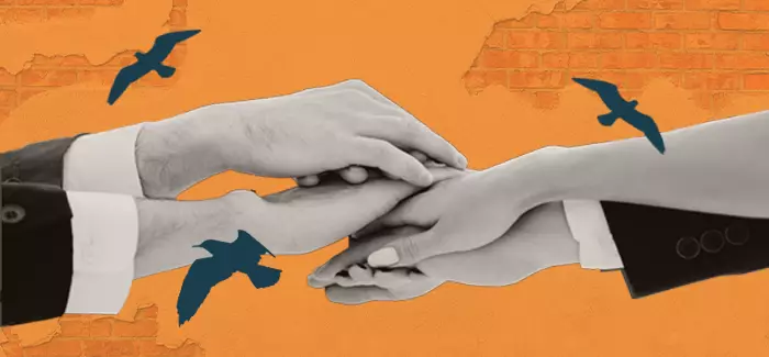 Four hands stacked on top of each other against a brick background with birds flying by to represent community corrections programs.