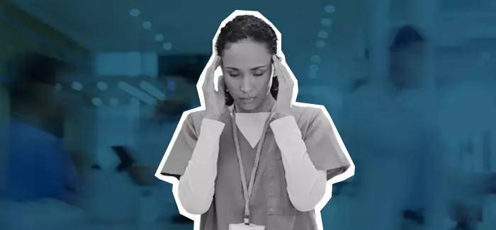 Nurse sitting with her hands in her hands together, looking worried and stressed like she could be suffering from nurse burnout.