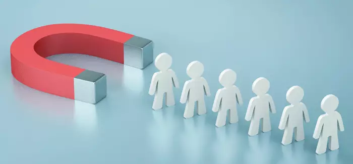 A magnet attracting a line of wooden cutouts of people to signify employee retention