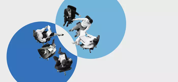 Two groups of three people each sitting on chairs facing each other in a meeting to represent becoming a skills-based organization