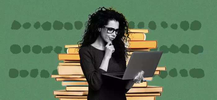 Stacks of books in the background with a woman looking at her laptop with a quizzical look on her face wonder "is a master's degree worth it?"