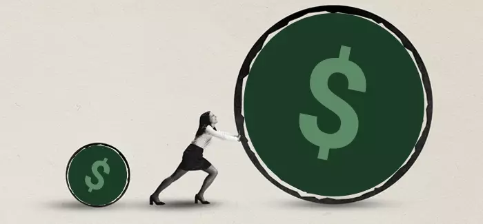 An entrepreneur pushing a giant symbol of money to signify the process of how to fund a business startup