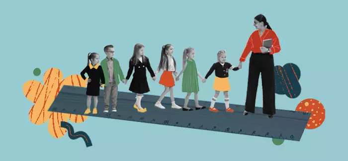 An early childhood education teacher leads a line of children walking on a path that looks like a ruler