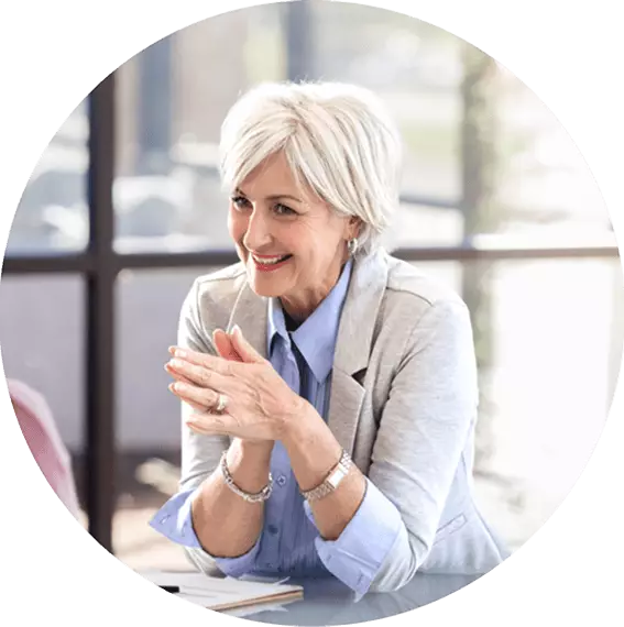 Professional sitting at a table and smiling, representing the role of a social work case manager.