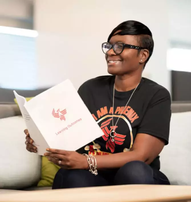 A smiling person reading a printed booklet, representing key learning outcomes in the online bachelor’s in social work. 