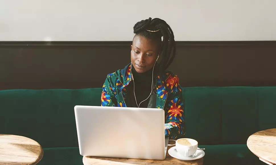 A professional seated in a coffee shop updates her LinkedIn profile