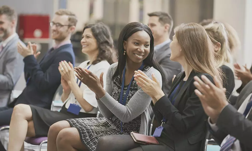 Crowd clapping while at networking event.