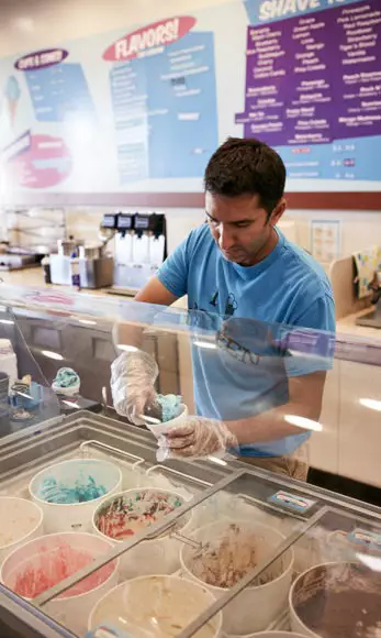 Nindi scoops ice cream for a customer in his store