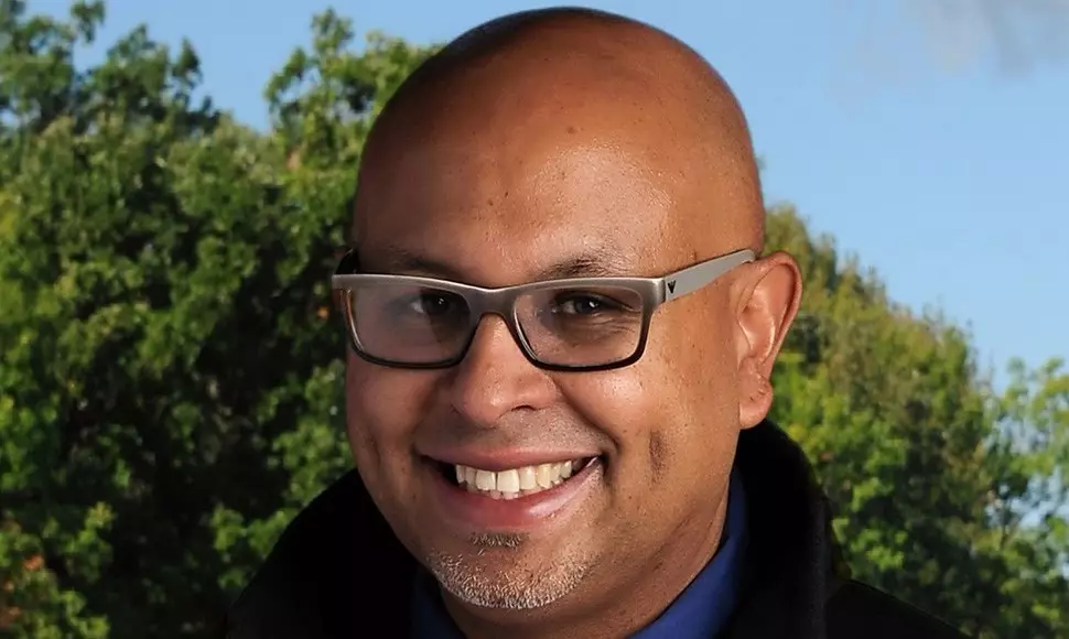 Christopher Wilson smiling and wearing glasses