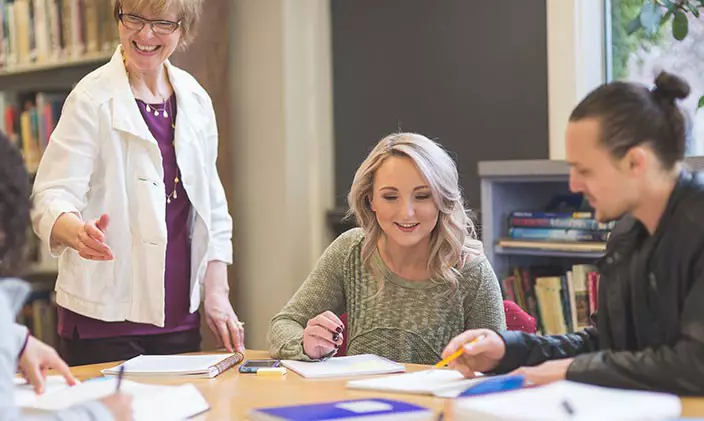 Students learning at a table with instructor overseeing