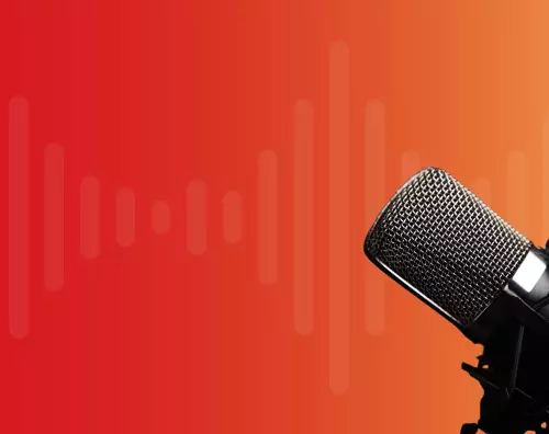 Black and silver microphone in right hand of frame against a red and orange background.