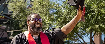 A happy bachelor's degree graduate waves to friends