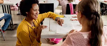 A teacher works with her pupil on a paper