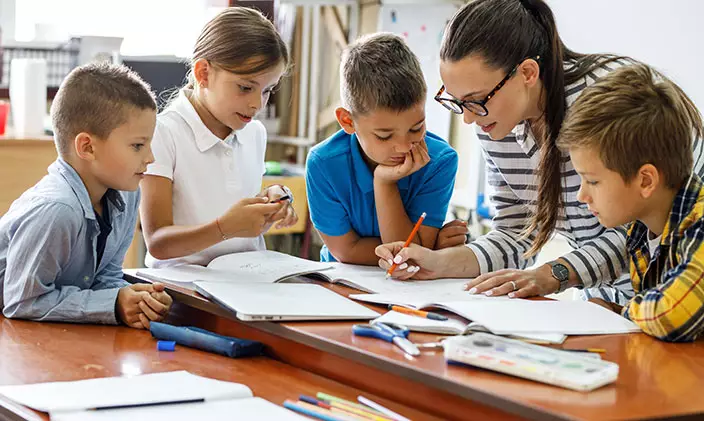 An elementary teacher works with a group of young students