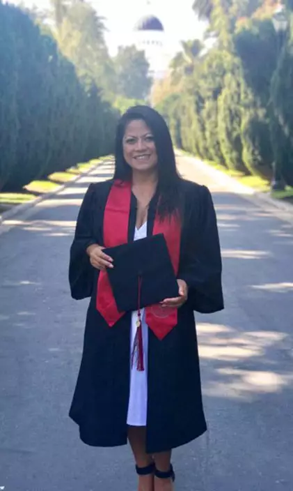 Emely Arienza wearing full graduation regale in front of government building