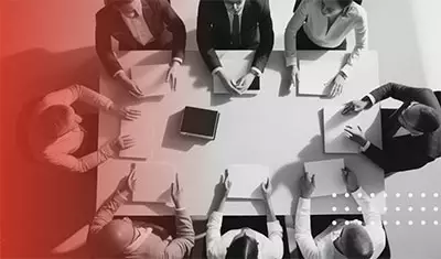 A group of people gathered at a conference table to signify the experts at University of Phoenix