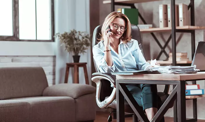 Female business entrepreneur writing notes while on the phone 