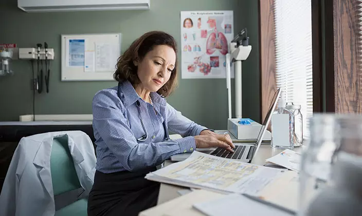 A health professional works on a laptop