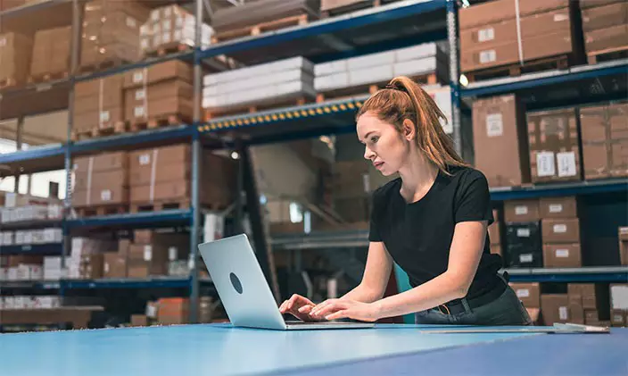 Female supply chain manager works on a laptop in a warehouse