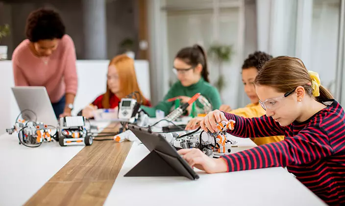 Group of children fiddle with robots in a classroom