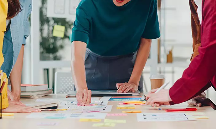 Group of coworkers looking over design strategy on post-it notes