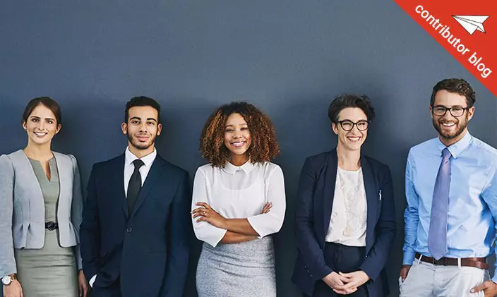 group of smiling businesspeople standing against grey background