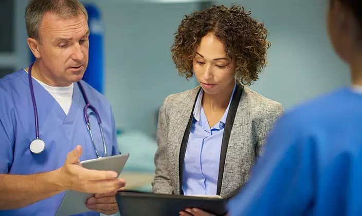 Female hospital administrator collaborating with a male doctor to signify healthcare management vs. healthcare administration
