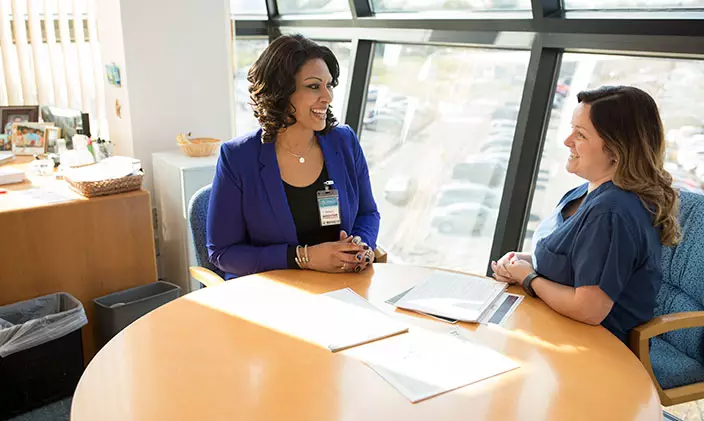 Two people during a healthcare interview smile across the table