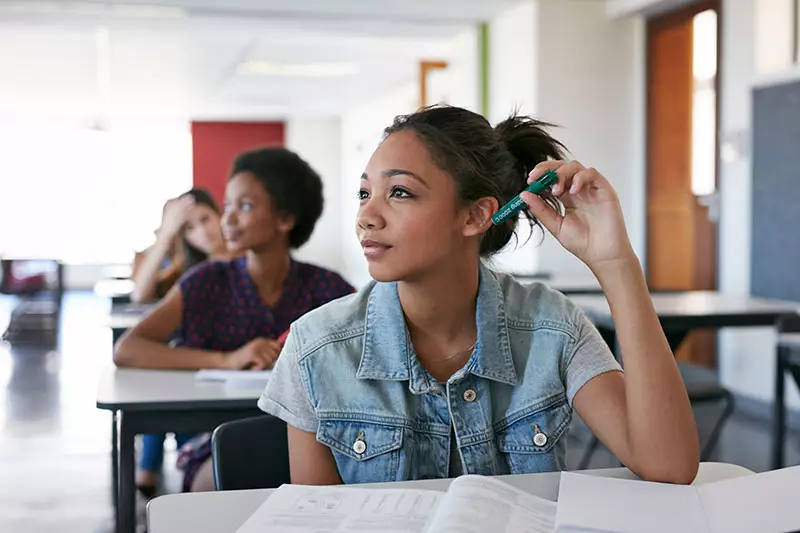 High school students shown in a public school classroom, listening to a presentation