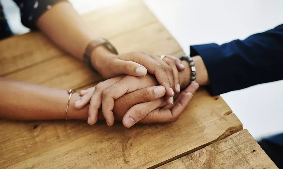 Hands holding each other on a wooden table